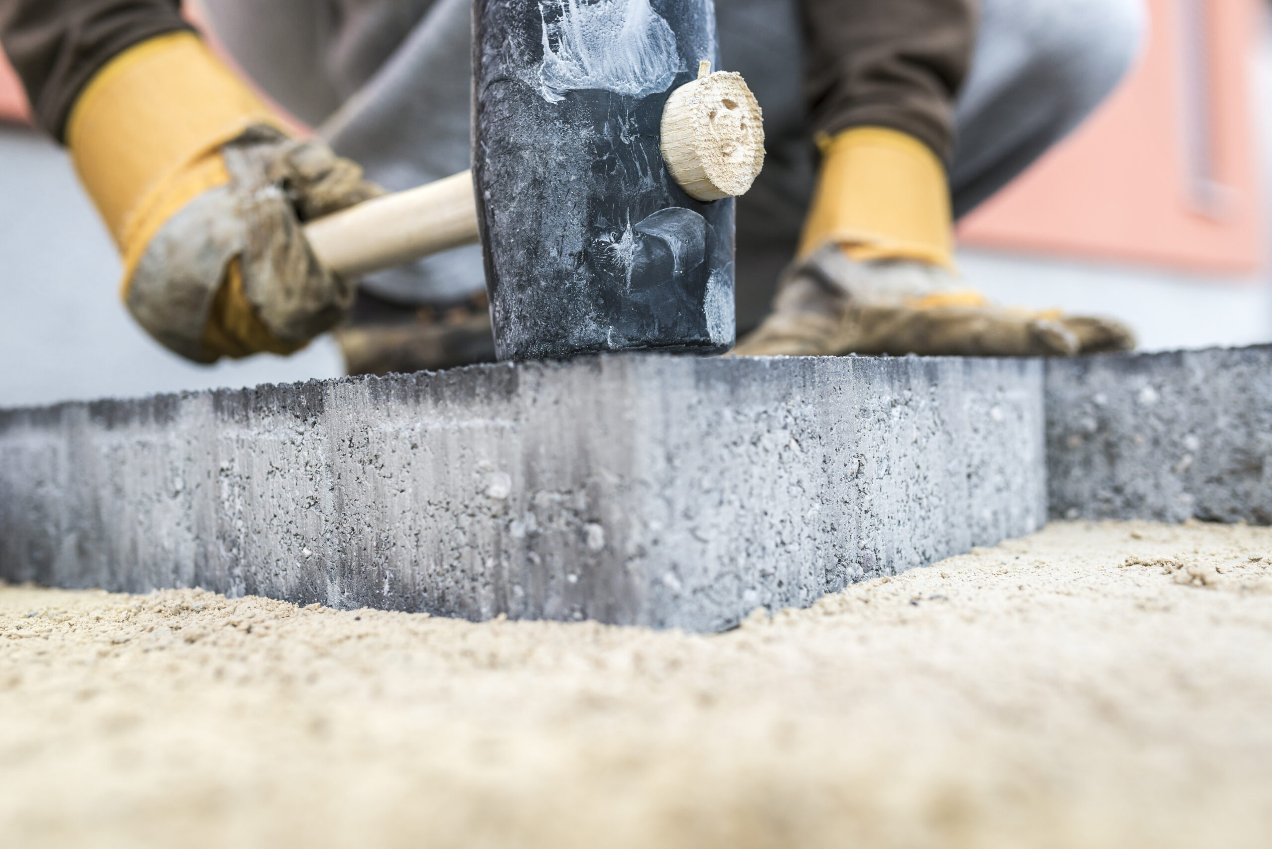 Pflastern builder tamping down a new paving slab or brick 2021 08 26 22 28 02 utc scaled erdbau tiefbau erdbauarbeiten erdarbeiten